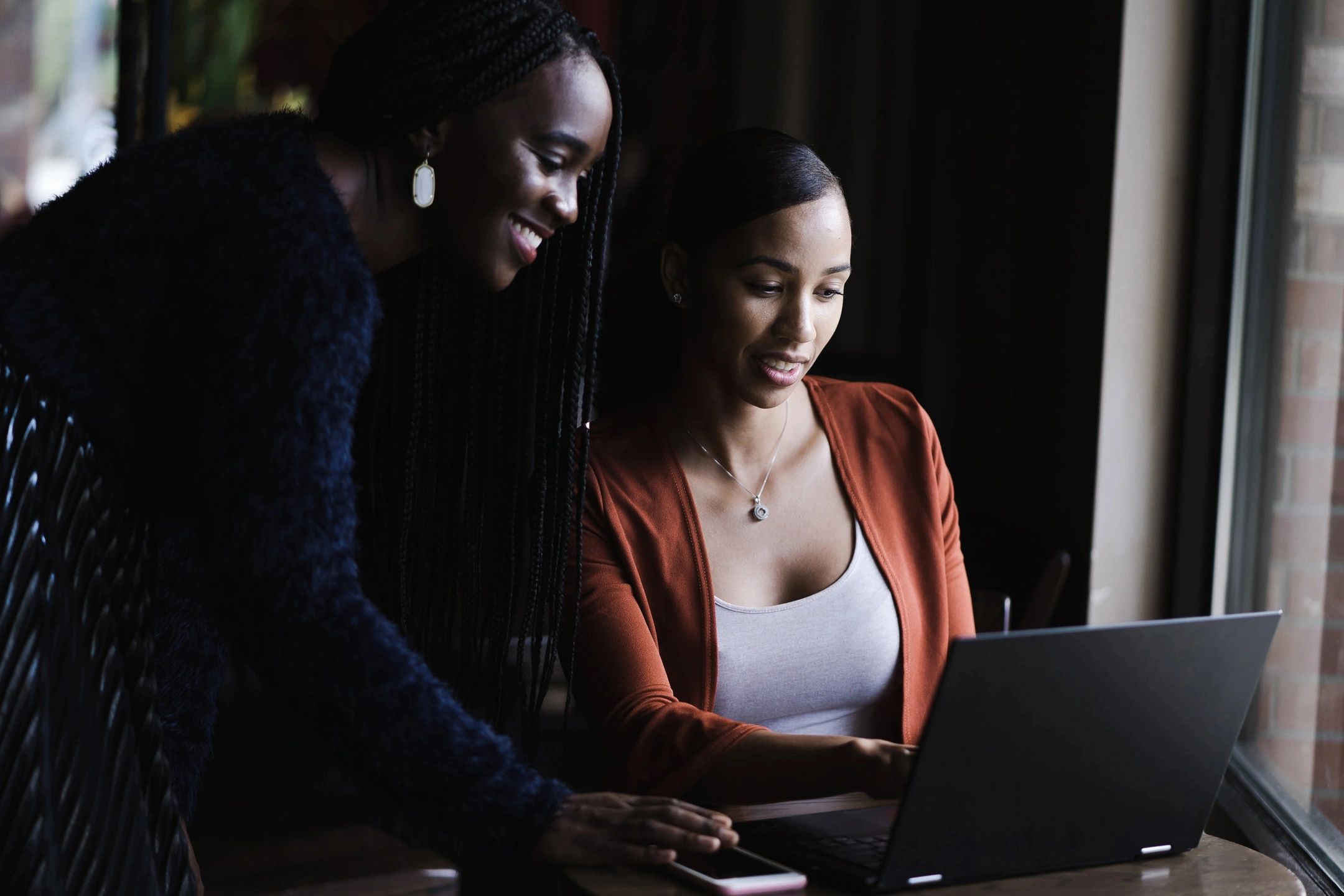 Two women in front of a laptop collaborating.