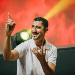 Deaf man standing in front of a stage light while speaking to his audience in American Sign Language (ASL).