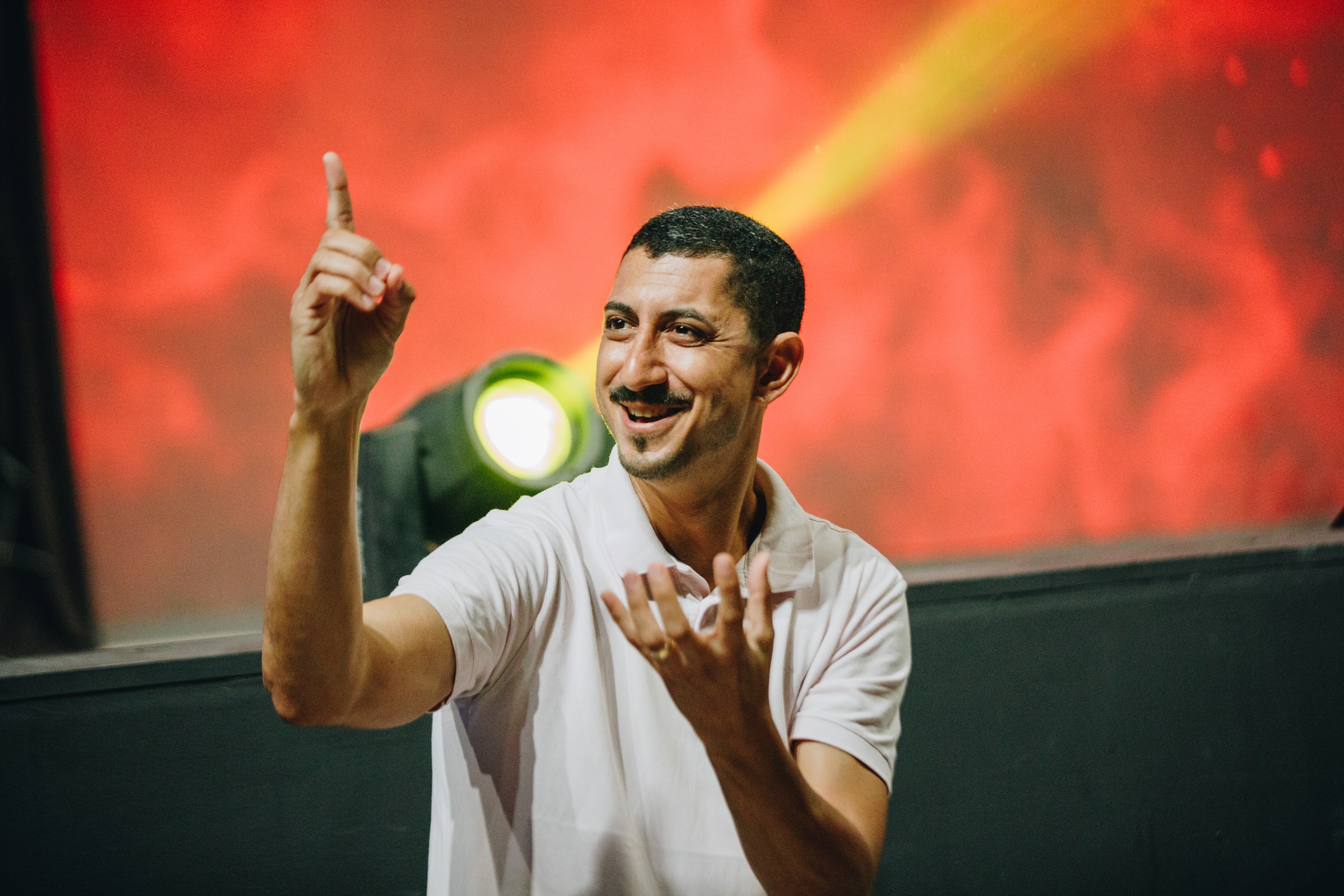 Deaf man standing in front of a stage light while speaking to his audience in American Sign Language (ASL).